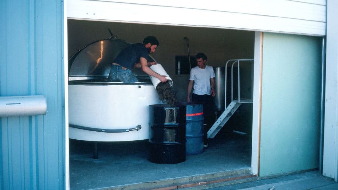 men emptying buckets into barrels