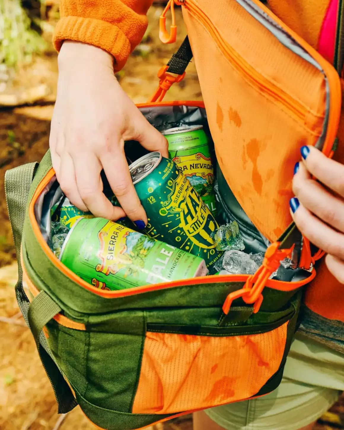 Hands reaching into soft cooler full of cans of Sierra Nevada Pale Ale and Hazy Little Thing