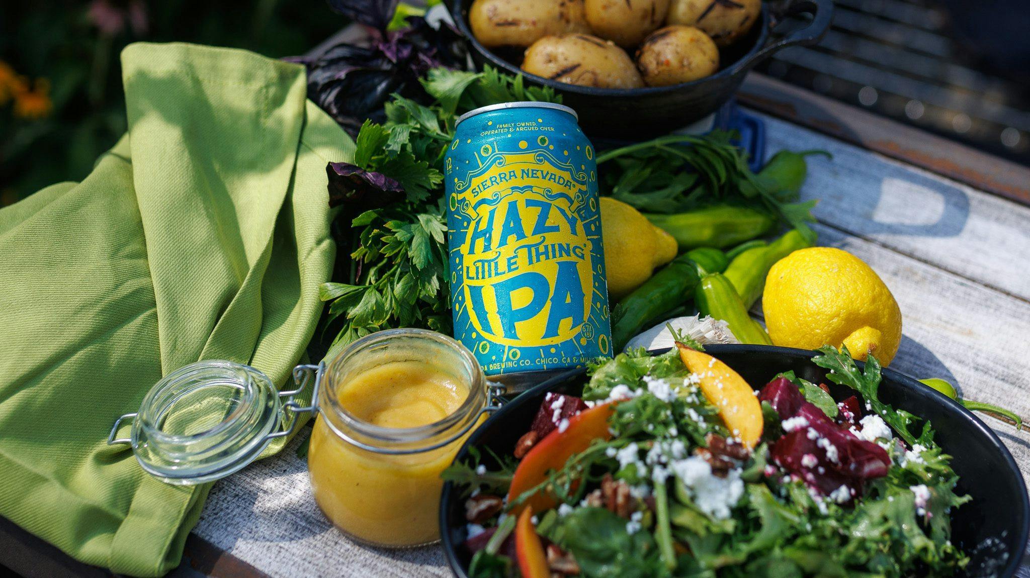 A can of Hazy Little Thing IPA next to a fresh salad and a mason jar of lemon vinaigrette