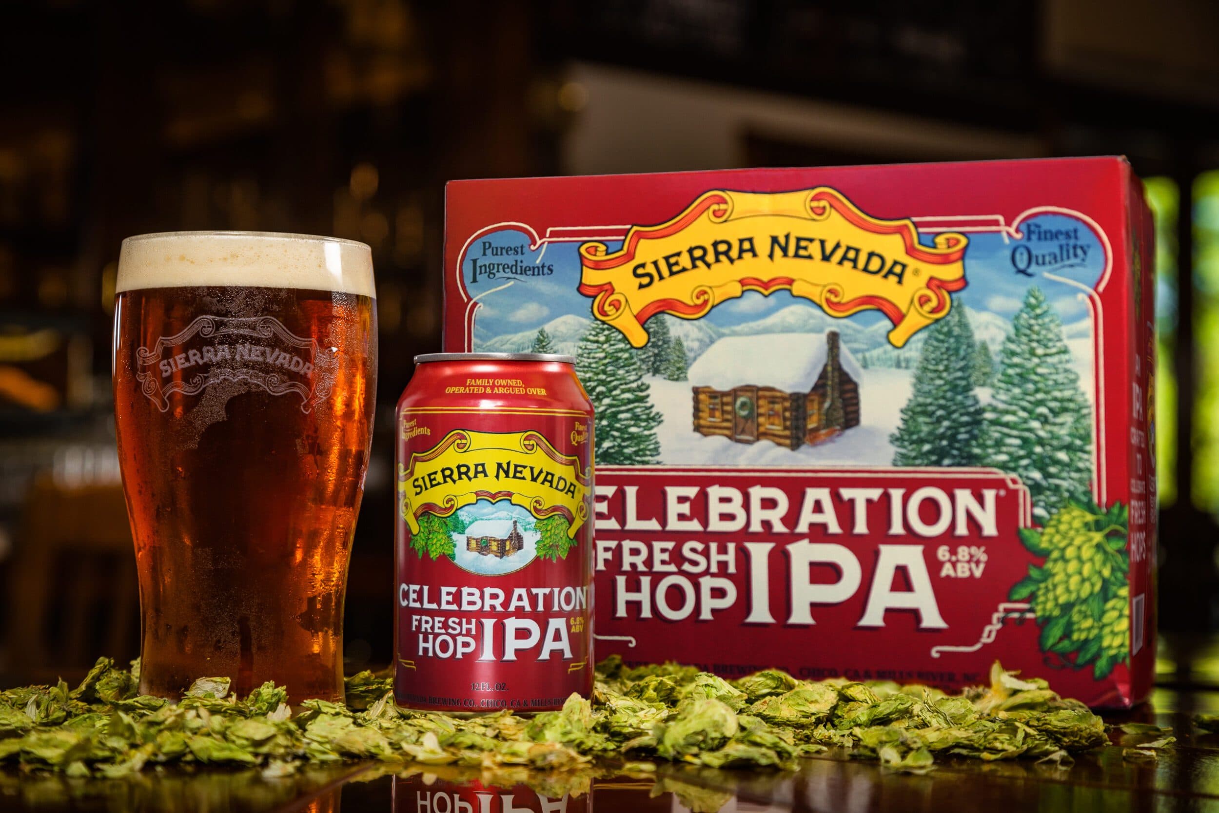 Celebration IPA can, pint and 12-pack in bed of hops