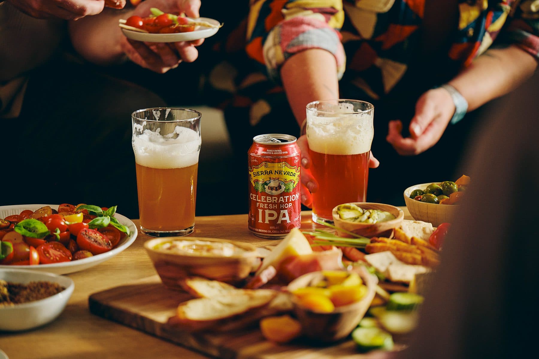 A can and glass of Sierra Nevada Celebration IPA on a coffee table covered with snack foods