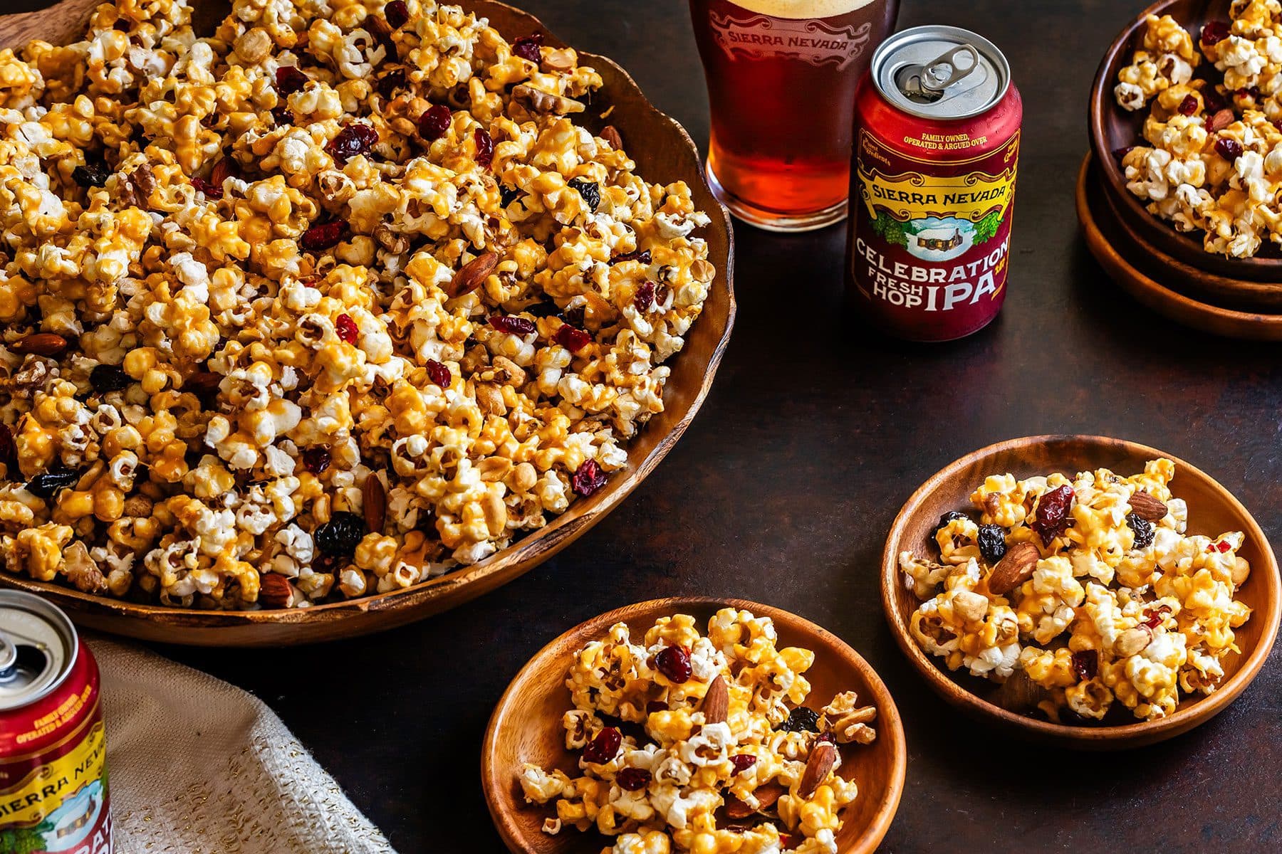 Bowls of caramel popcorn next to a can and glass of Celebration IPA