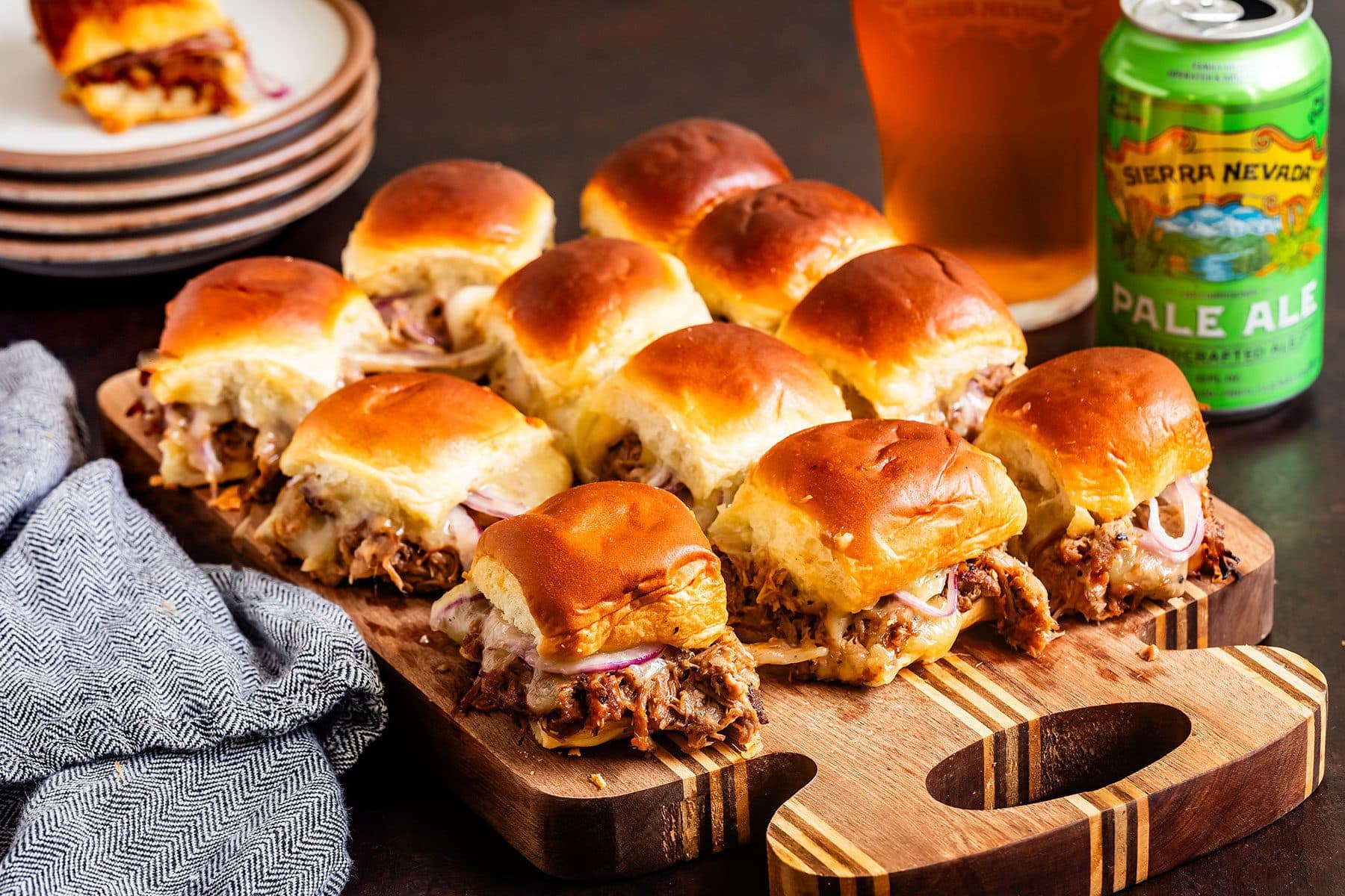 Rows of pulled pork sliders on a cutting board next to a can and glass of Sierra Nevada Pale Ale